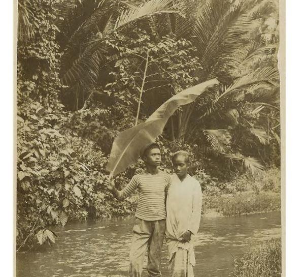 Foto seorang pria dan seorang wanita menyeberangi sungai di Ambon pada tahun 1900.  (Perpustakaan Universitas Leiden)